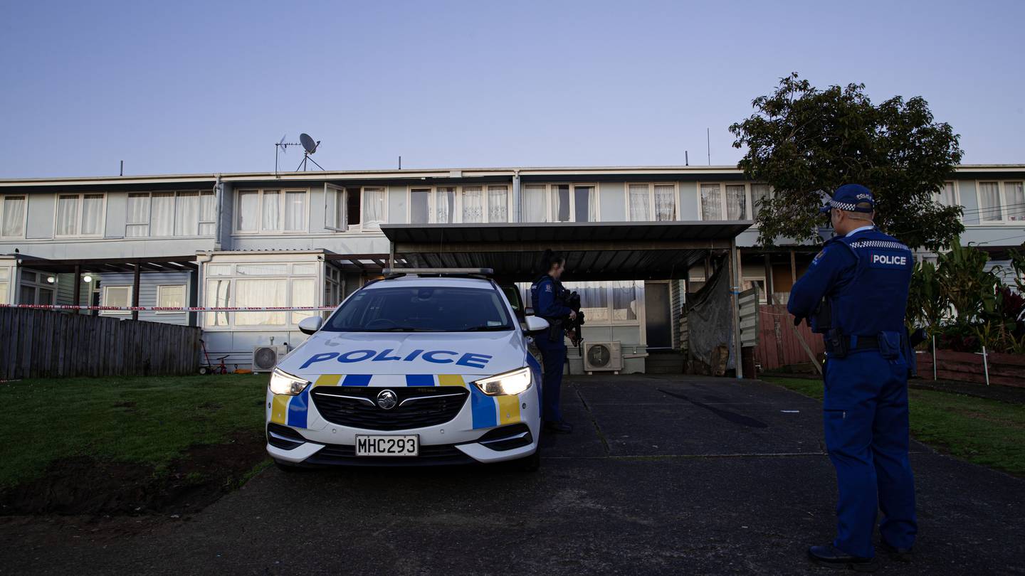 Armed police stand guard at an address in Auckland's Ōtara after it was shot at on Saturday evening. Photo / Hayden Woodward