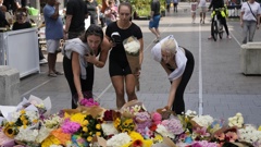 Three women place flowers as a tribute near a crime scene at Bondi Junction in Sydney. Photo / AP