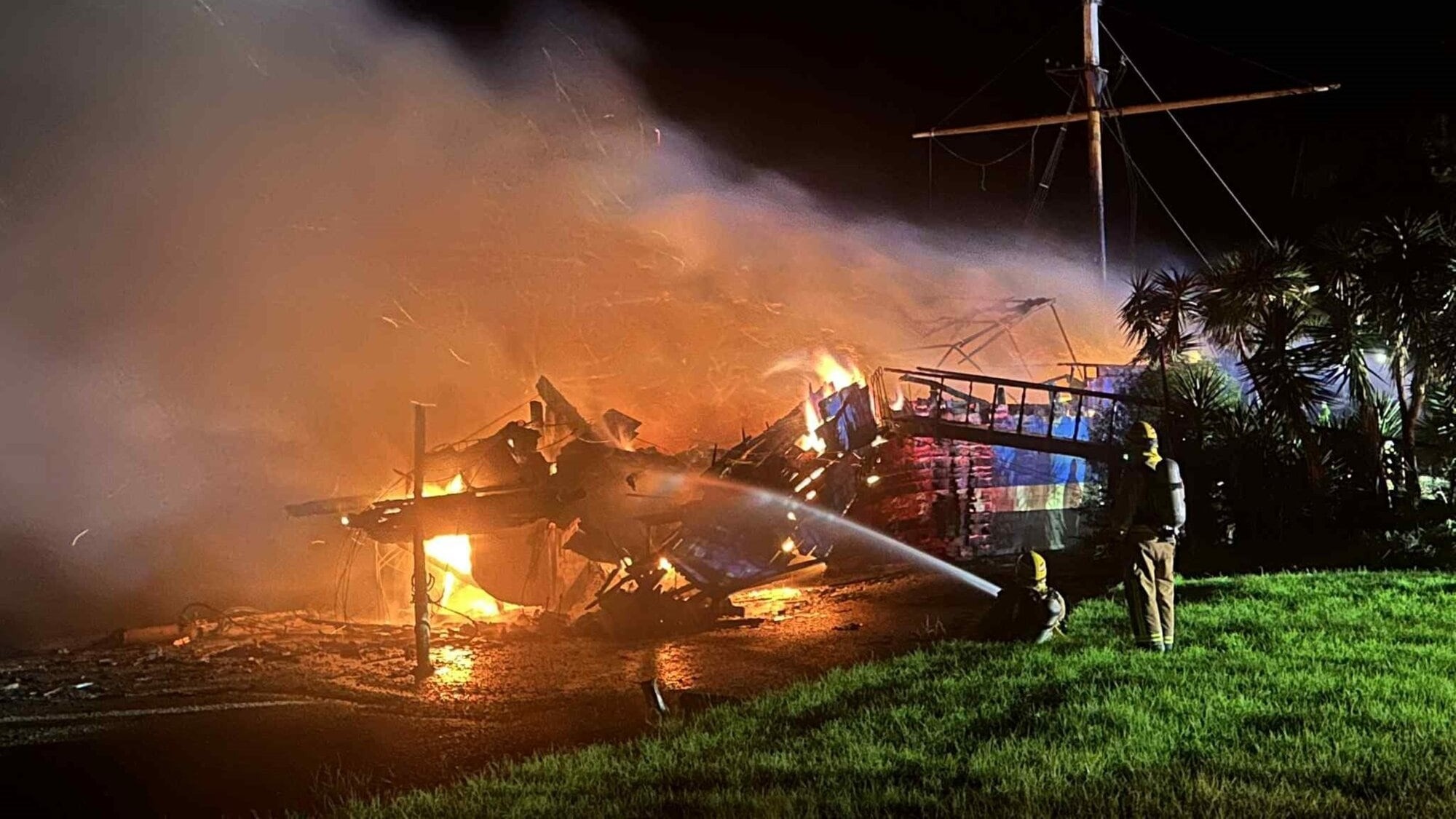 Firefighters work to extinguish a blaze on a historic ship The Tui by the Waitangi Bridge in Paihia.  Photo / Derek Gerritsen