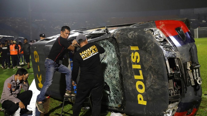 Officers examine a damaged police vehicle following a clash between supporters of two Indonesian soccer teams at Kanjuruhan Stadium. Photo / AP