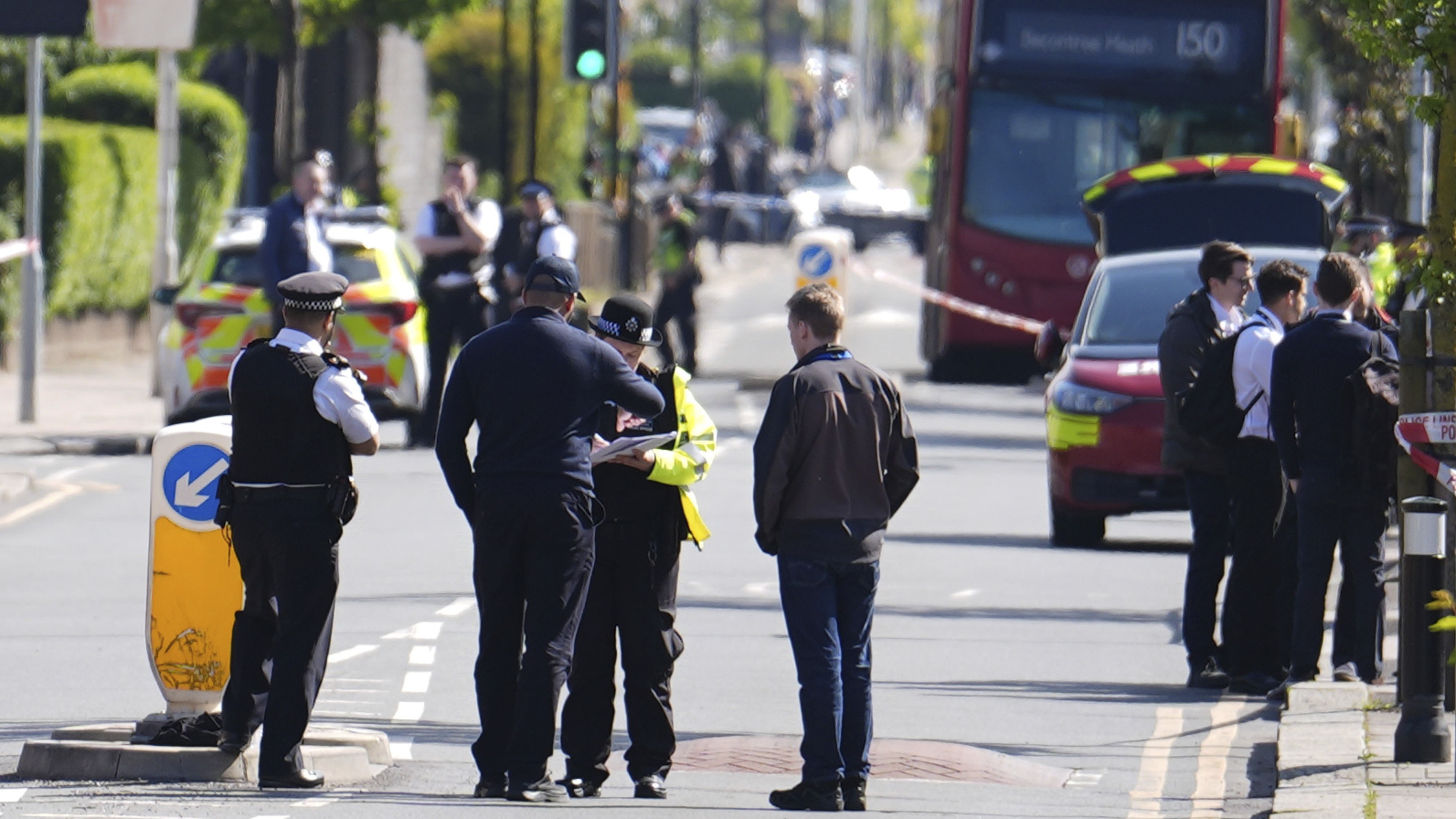 Police talking to members of the public at the scene in Hainault, north east London, Tuesday, April 30, 2024 after reports of several people being stabbed at a Tube station. (Jordan Pettitt/PA via AP)
