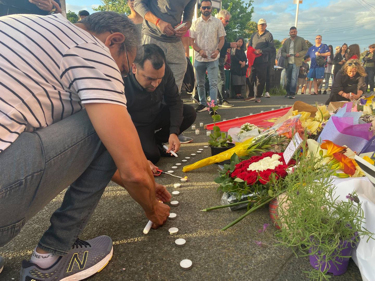 Mourners light candles in memory of slain dairy worker Janak Patel last night. Photo / George Block