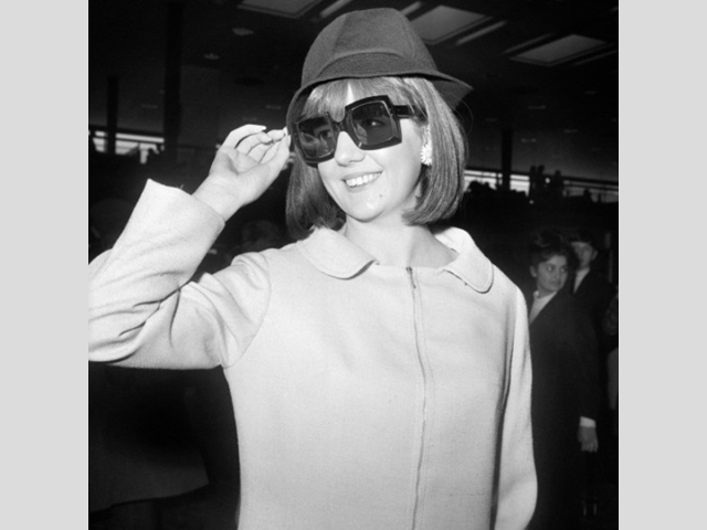 The Liverpudlian singer hiding behind big dark sunglasses at Heathrow Airport, while on her way to New York to appear on the Ed Sullivan Show.