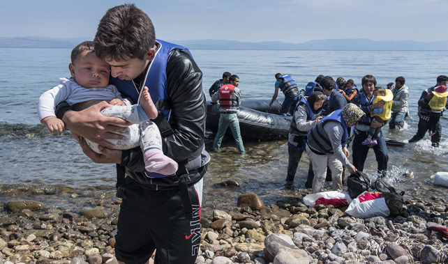 A refugee from Afghanistan carries a baby on arrival on the shores of Lesbos near Skala Skamnias, Greece on June 2, 2015 (Getty Images) 