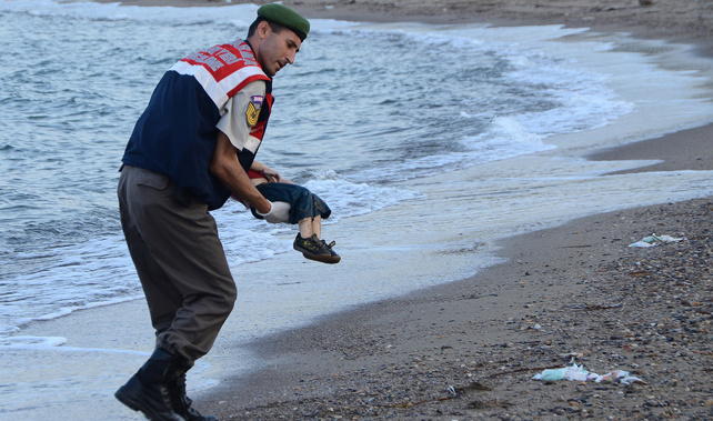 A Turkish police officer carries a migrant child's dead body off the shore of Bodrum, south Turkey (Getty Images) 