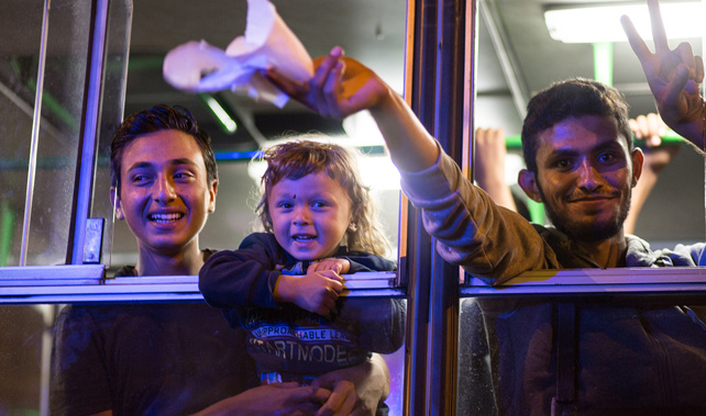 Refugees celebrate after boarding buses bound for Austria (Getty Images) 