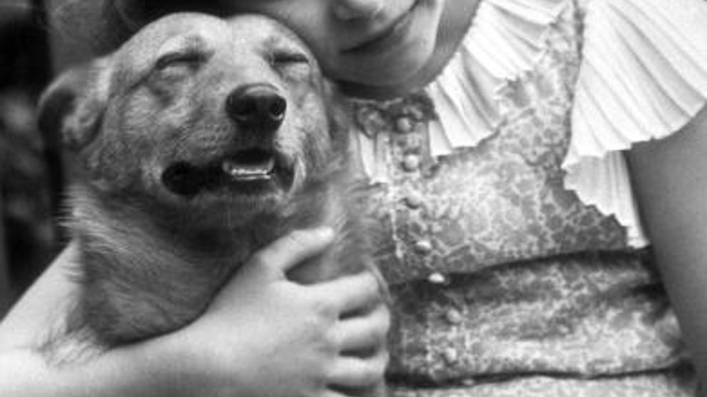 July 1936: Princess Elizabeth hugging a corgi dog