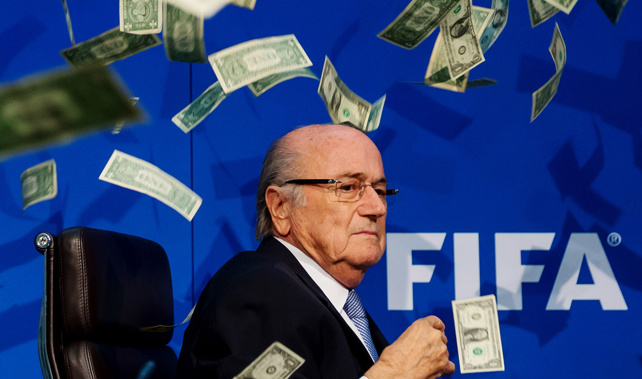 A comedian throws fake money over Sepp Blatter during a press conference (Getty Images) 