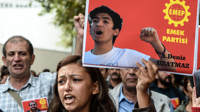 A demonstrator holds a placard of one of the people killed in the blasts (Getty Images