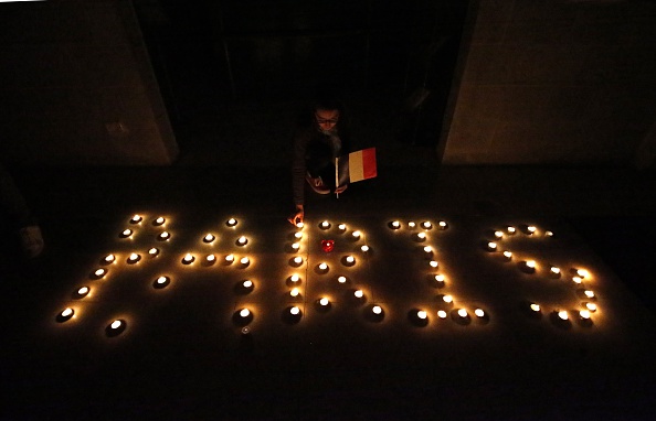 Palestinians arrange candles to spell, Paris, during a candlelight vigil outside the French Cultural Center in the West Bank city of Ramallah