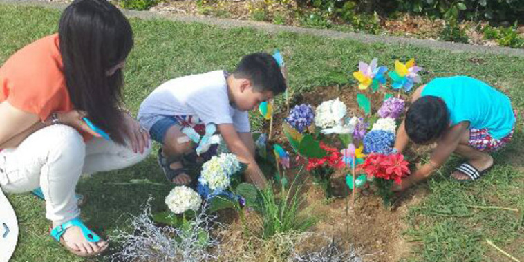 Nadene Lomu and her two sons place flowers on Jonah Lomu's grave at Manukau Memorial Gardens.