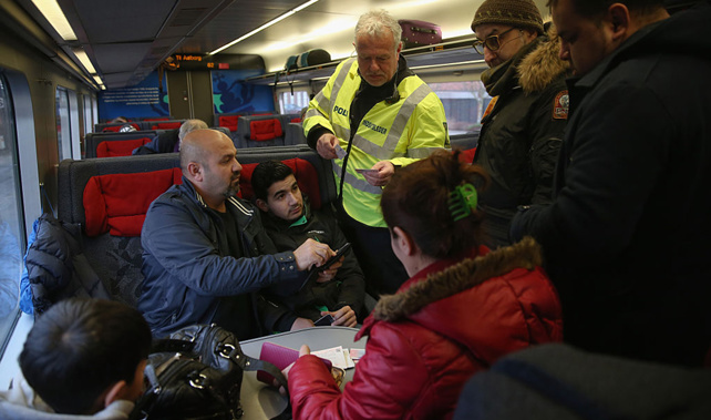 A Danish policeman checks the identity papers of passengers on a train arriving from Germany (Getty Images)