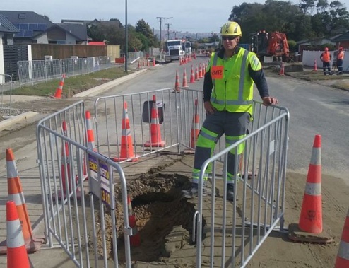 Site traffic management supervisor Phillip Jonker beside a 3m long, 1m deep sinkhole which has opened up on a Christchurch street after yesterday's quake (Kurt Bayer) 