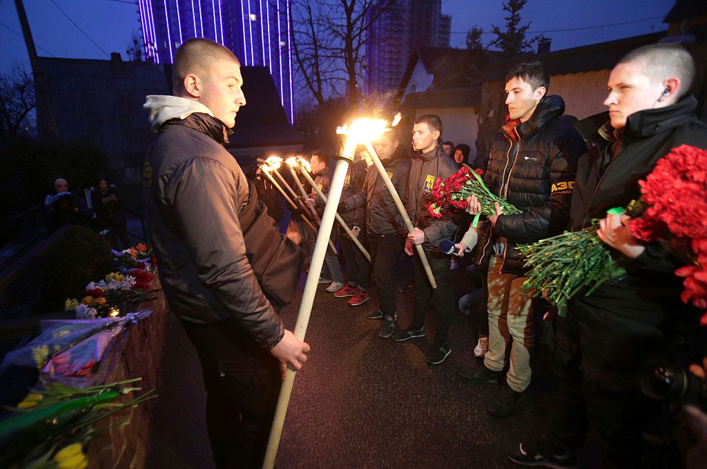 Servicemen of Azov, Ukrainian volonteers battalion, hold torches in front of floral tributes during a ceremony in front of the Belgian embassy in Kiev