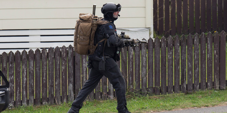 An Armed Offenders Squad member moving into position near where gunman Pita Rangi Te Kira is holed-up in a house on Kokiri Cres in Porirua. (NZ Herald/Mark Mitchell)
