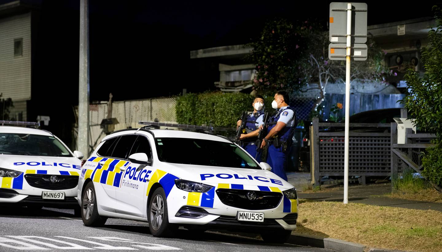 Armed police stand guard at a street in the East Auckland suburb of Pt England. (Photo / Hayden Woodward)