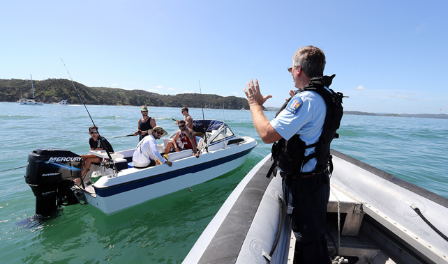 Police officer in charge of the Maritime Unit talks to boaties near Russell about water safety (NZ Herald)