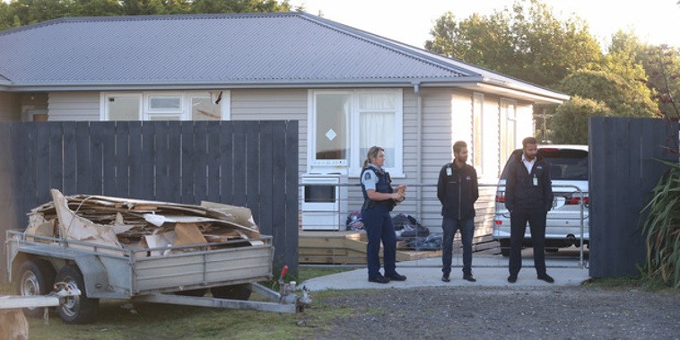 Police and security stand outside a house on Factory Rd in Waiuku where a child died suddenly.