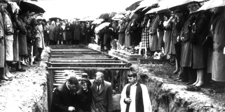 Accompanied by a clergyman, mourners leave the mass grave of the 19 miners killed in the Strongman Mine disaster on January 19, 1967 (New Zealand Herald archive)