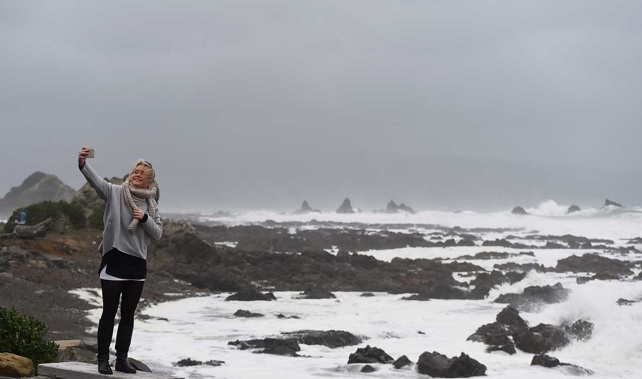A Wellingtonian takes a photo against the backdrop of a storm (Getty Images) 