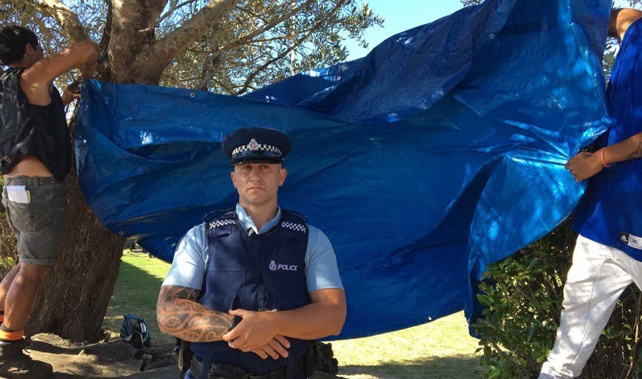 A policeman watches over spectators as a tarpaulin is raised over the entrance to Te Tii (Audrey Young) 