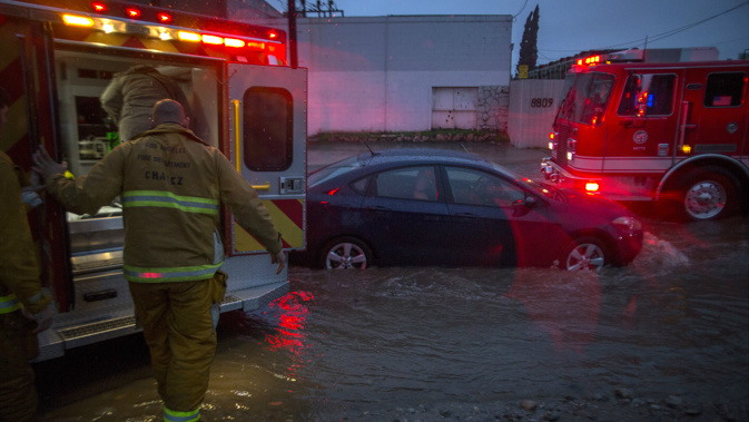 Firefighters prepare to transport a patient by ambulance at the scene of a car stuck in flooding in Southern California. (Getty)