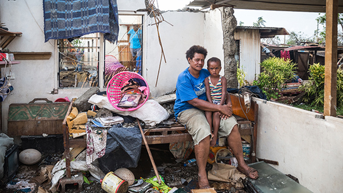 A Fijian family surrounded by the devastation the cyclone caused last year (Getty Images).