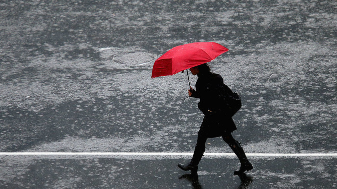 A pedestrian crosses an Auckland intersection during heavy rain. (Getty)