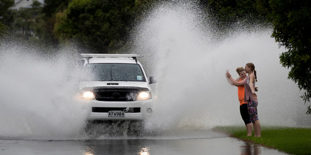 Sisters Lily-Portia McLaughlin, 17 and Ella-Grace McLauglin,14, have some fun as drivers make their way through Portland Road, Remuera. Photo / Brett Phibbs