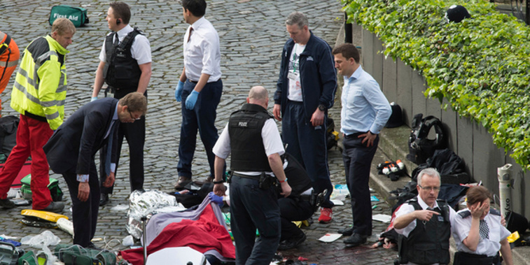 MP Tobias Ellwood, left, stands amongst the emergency services after assisting the police officer. Photo / AP