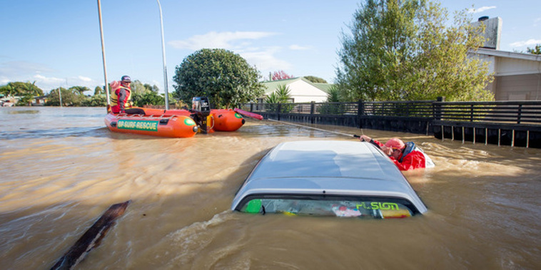 Members of the Mount Maunganui Lifeguard Service check a submerged car in Edgecumbe (NZ Herald) 