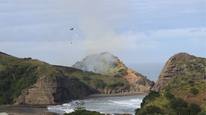 A second helicopter has been sent to Piha where a number of homes are at risk from a large scrub fire. (Alistair Wilkinson/Twitter)