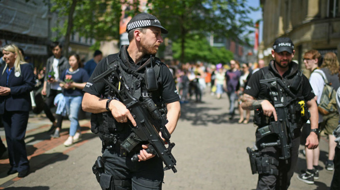 Armed police patrol as members of the public queue to lay flowers in St Ann's Square in memory of those who lost their lives in the Manchester Arena attack. (Getty)