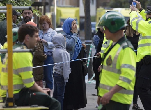 Emergency service responders and local people gather at a cordon near the site of a massive fire in west London. Photo / AP