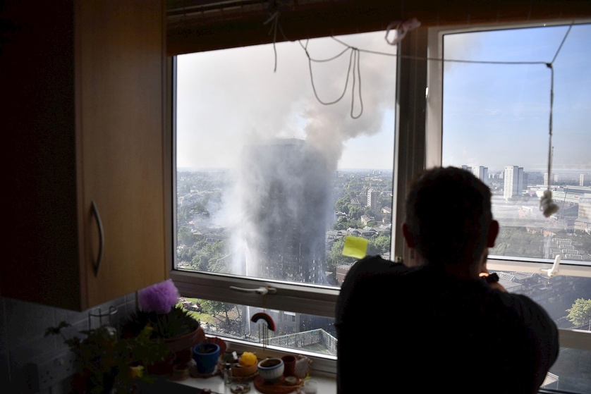 A photographer takes photos as smoke continues to rise from the building after a huge fire engulfed the 24 storey residential Grenfell Tower block in Latimer Road, West London. Photo / Getty Images