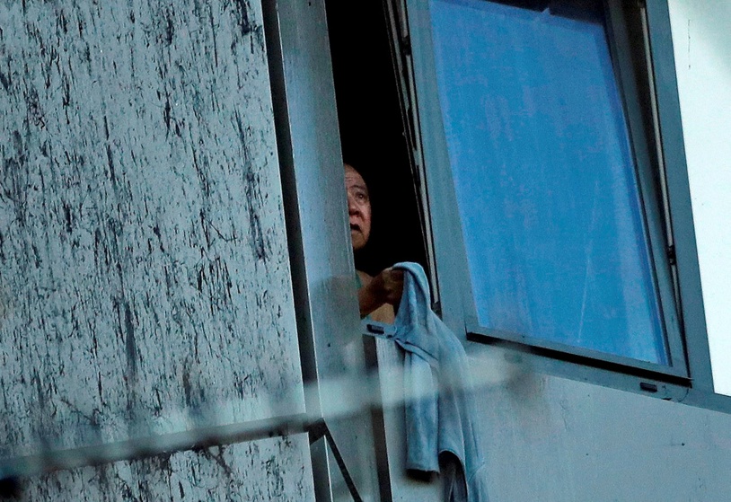 A distressed, trapped man waves an item of clothing from his window. Photo / AP