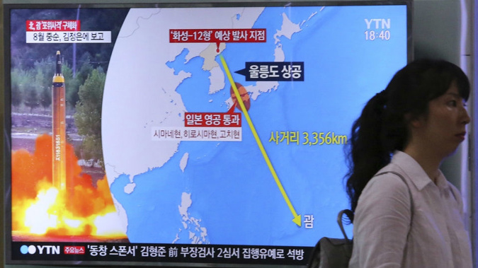 A woman passes by a TV screen showing North Korea's threats to strike Guam with missiles at the Seoul Train Station in Seoul, South Korea. Photo / AP