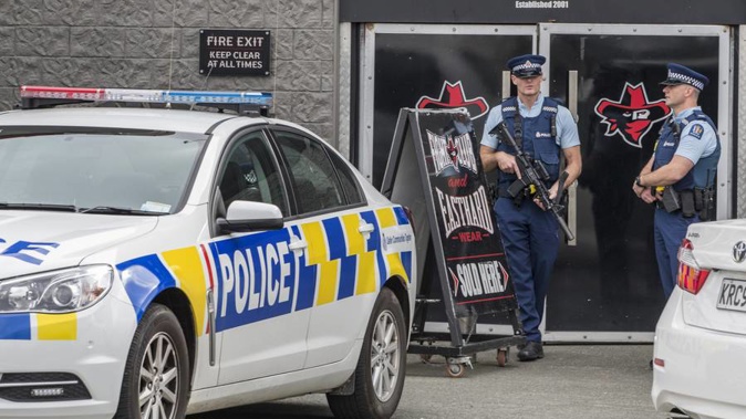 Armed police officers stand guard as they raid the Head Hunters Motorcycle Club clubrooms in Marua Road, Ellerlie. (Photo / NZ Herald)