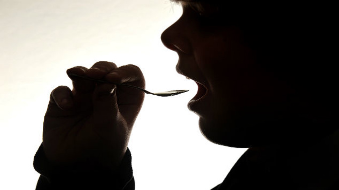 teenage boy doses himself a Tea-spoon filled with night time cough relief linctus (Photo \ Getty Images) 