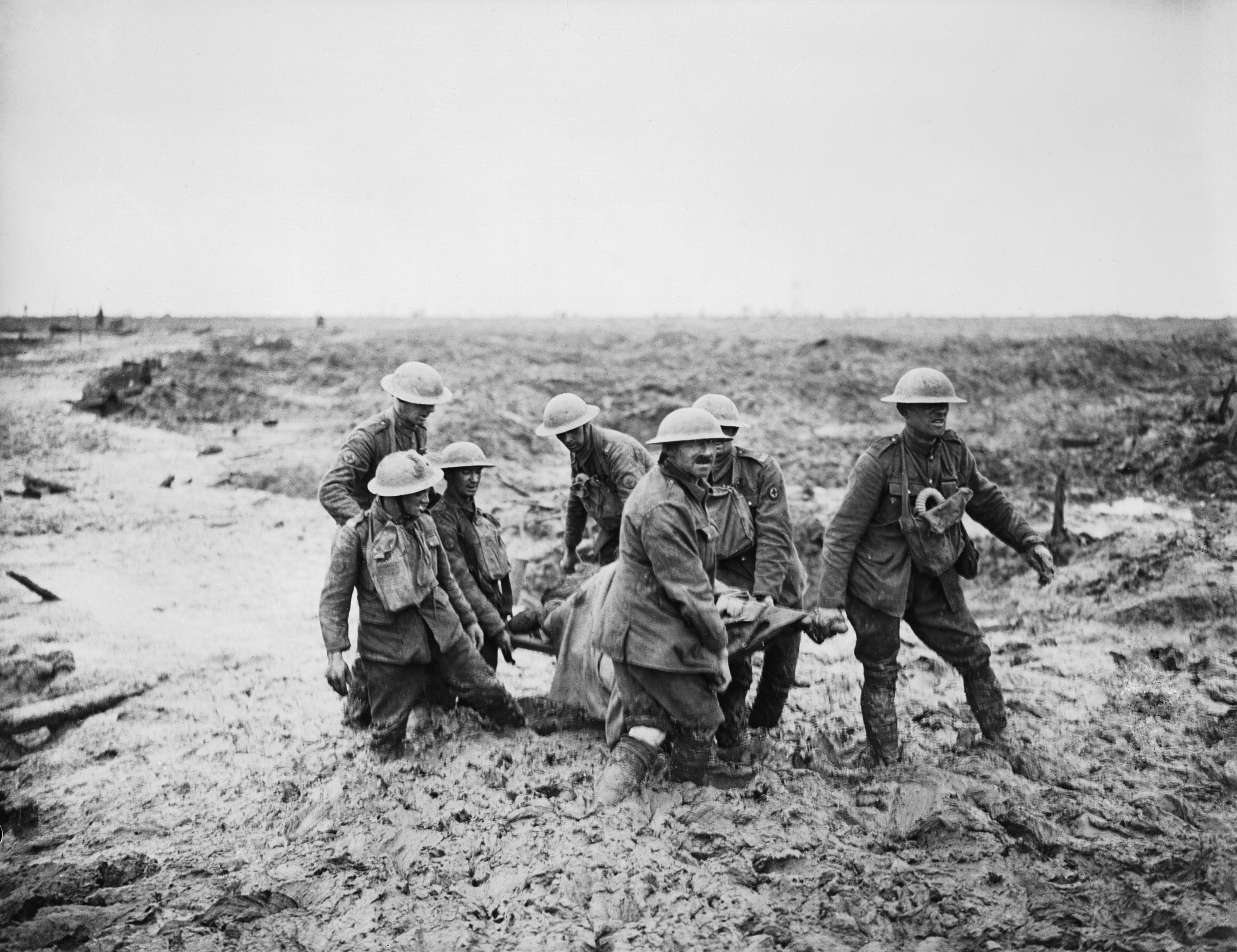 Stretcher bearers struggle in mud up to their knees to carry a wounded man to safety near Boesinghe 