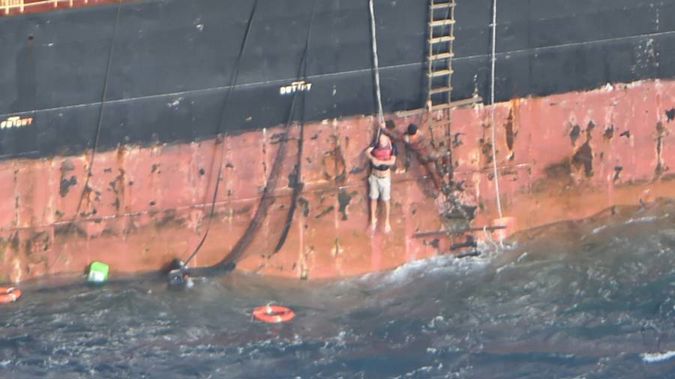 A dramatic photo released by the NZDF shows the stricken Norwegian sailor being hoisted up the side of MV Southern Lily by crew as a life ring bobs in the large swells below him. (Photo / NZDF)