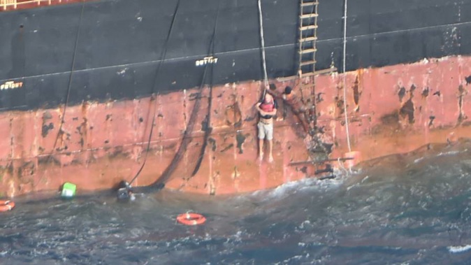 A dramatic photo released by the NZDF shows the stricken Norwegian sailor being hoisted up the side of MV Southern Lily by crew as a life ring bobs in the large swells below him. (Photo / NZDF)