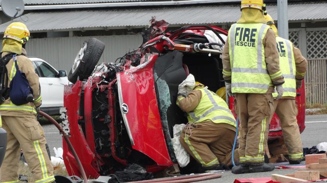 Firefighters work to free two people trapped in a vehicle involved in a two-vehicle crash at Maheno, 14km southwest of Oamaru, yesterday. (Photo / Daniel Birchfield)