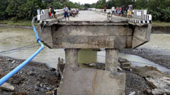 People gather on a bridge which was damaged by the onslaught of the flooding brought about by tropical storm Tembin in the Philippines. Photo / AP