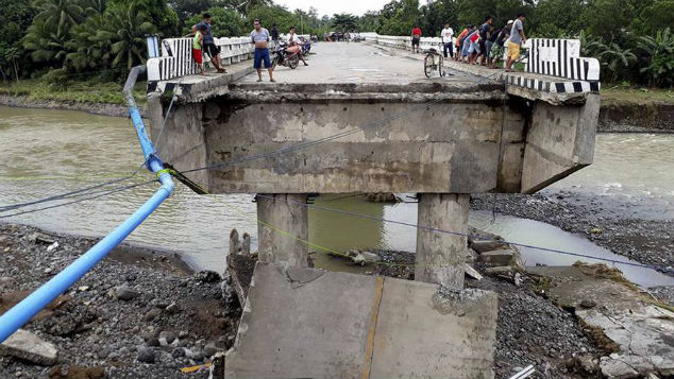 People gather on a bridge which was damaged by the onslaught of the flooding brought about by tropical storm Tembin in the Philippines. Photo / AP