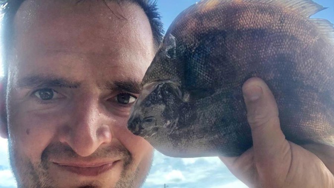 Russell Hogg with the flounder that fell from the sky and onto his head. (Photo / Supplied)