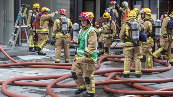 Firemen work outside the Park Residence high rise building on the corner of Swanson Street and Albert Street. (Photo / NZ Herald)