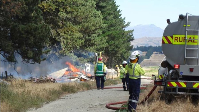 Firefighters work at the scene at Lake Hawea. (Photo / Otago Daily Times)