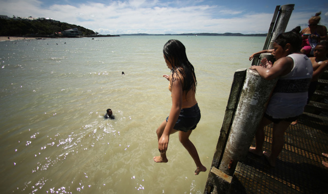 Children jump of the wharf on the beach at Maraetai (Getty Images)
