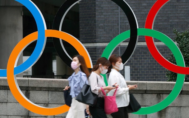 People wearing face masks walk past the Olympics Rings statue in Tokyo. (Photo / AP)